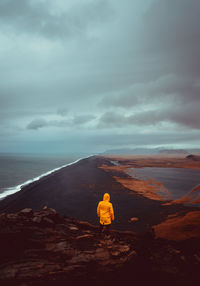 Rear view of man looking at sea against sky