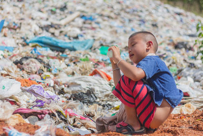 Side view of boy sitting on land