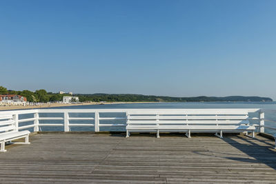 Pier over sea against clear blue sky