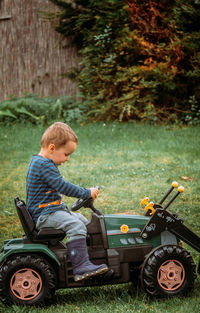 Side view of boy sitting by plants