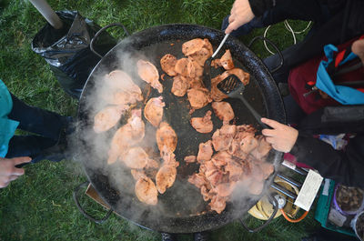 Meat being cooked outdoors on a large frying pan