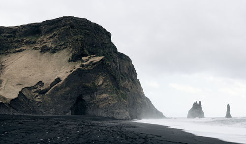 Rock formations on shore against sky