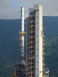 Crane by building against sky