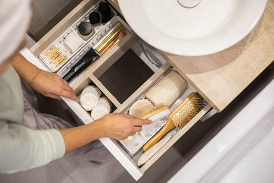 Midsection of woman arranging combs in drawer