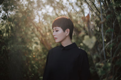 Portrait of young woman looking away in forest