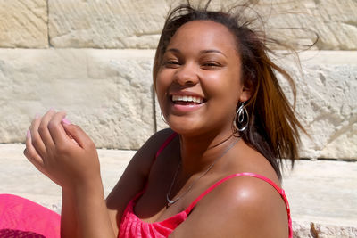 Portrait of smiling young woman standing against wall