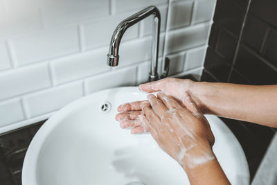 Midsection of man with arms raised in bathroom