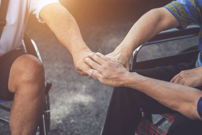 Cropped image of people on wheelchair stacking hands together