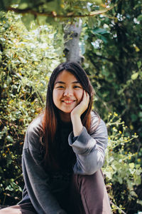 Portrait of smiling young woman standing against trees