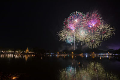 Firework display over river against sky at night