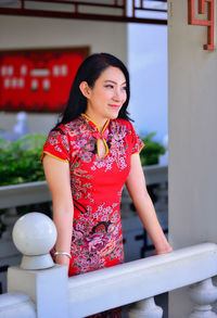 Young woman standing against red wall