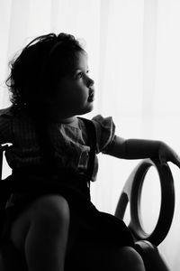 Cute baby girl looking away while sitting at home