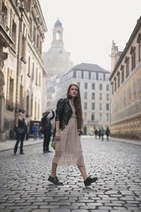 Full length of woman on street against buildings in city