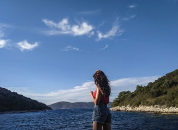 Woman standing by sea against sky