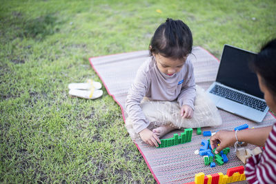 Side view of woman using digital tablet while sitting on field