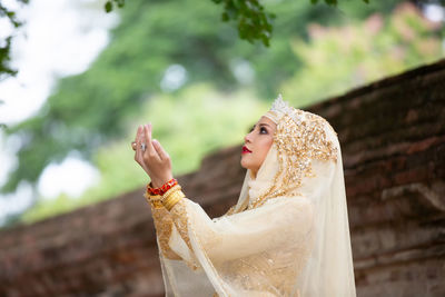 Side view of woman in hijab praying outdoors