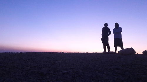 Friends standing on field against sky during sunset