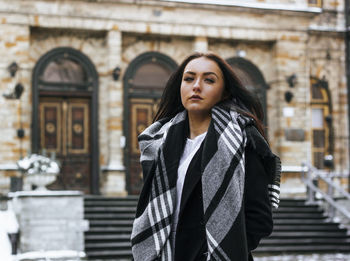 Portrait of young woman looking up in city