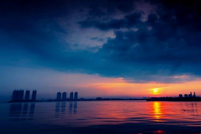 Scenic view of sea and buildings against sky at sunset