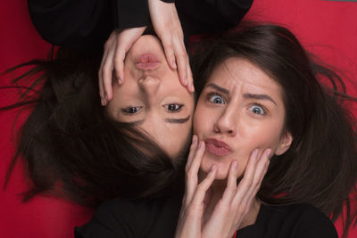 Portrait of young women lying over red background