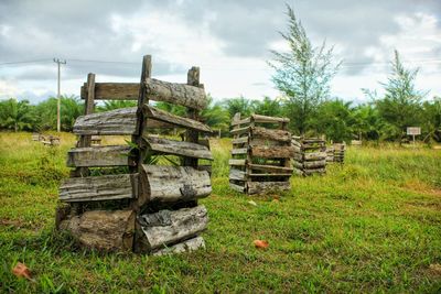 Stack of logs on field against sky