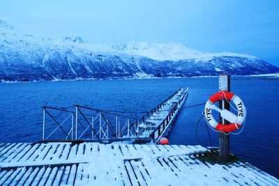 Lifeguard hut on snowcapped mountain by sea against sky