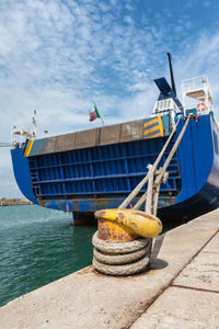 Fishing boat moored at harbor against sky