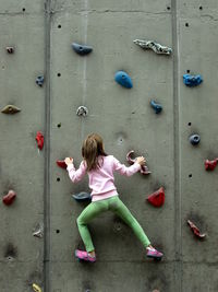 Rear view of girl climbing wall
