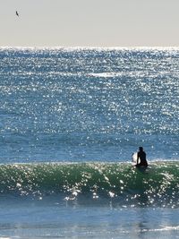 Silhouette man in sea against clear sky