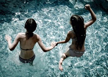 High angle view of girls jumping in swimming pool on sunny day