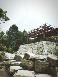 Stone wall by trees against sky