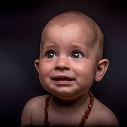Close-up of cute baby girl crying against black background