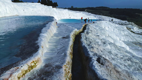 People on frozen river against sky