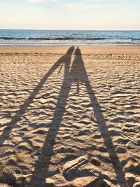 Shadow of people on beach against sky