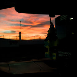 Silhouette of car against orange sky