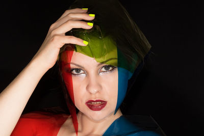 Portrait of fashion model with colorful plastic against black background