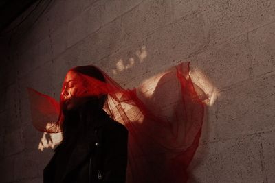 Close-up of woman with scarf standing against wall