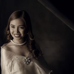 Portrait of smiling young woman against black background