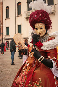 Venice carnival, italy. portrait of woman wearing traditional mask standing in city.