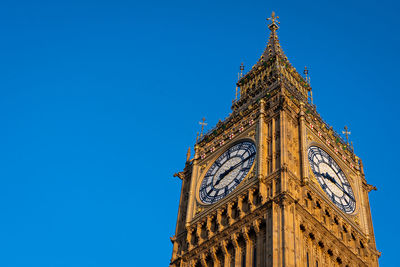 Low angle view of clock tower against clear blue sky