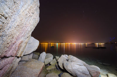 Rocks by sea against sky at night