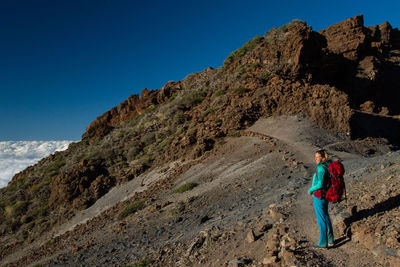 Woman standing on mountain against clear blue sky