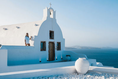 Woman standing at chapel by sea at santorini