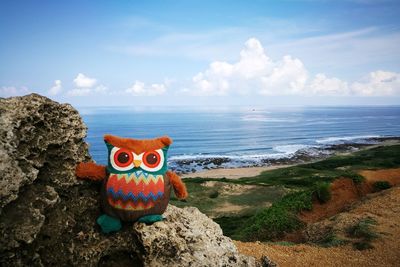 Stuffed toy by sea against sky
