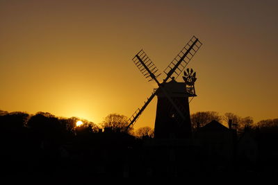 Silhouette of traditional windmill against sky during sunset