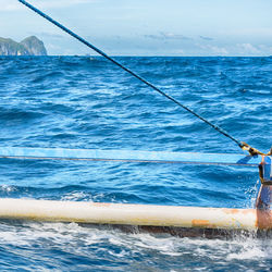 Rope tied to metal in sea against sky