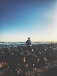 Full length of man on rock at beach against sky