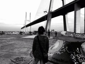 Rear view of woman standing by vasco da gama bridge at night