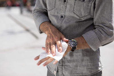 Old man cleaning hands with wet wipes, white