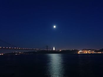 Illuminated bridge over river against sky at night